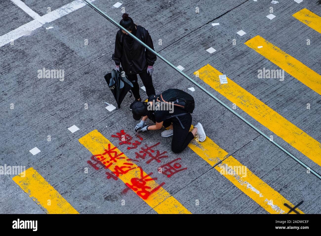 HongKong - Noviembre, 2019: El manifestante escribe graffiti en cruce de peatones durante el 2019 HongKong protestas, una serie de manifestaciones en Hongkong empezó como el proyecto de ley de enmienda de la Ley Anti-Extradition (Anti-ELAB) de movimiento. Foto de stock