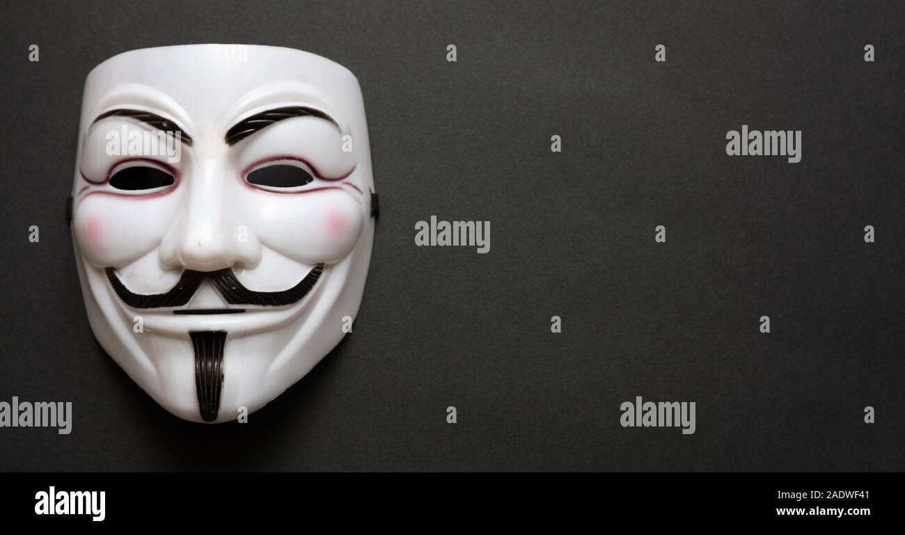 Vendetta máscara facial símbolo del grupo acktivist online anónimo contra el fondo negro, banner, copia el espacio. Foto de stock