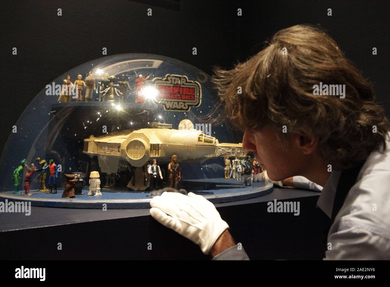 Sotheby's Gallery assistant Mateo Floris inspecciona una rara tienda de juguetes, visualización de 'El Imperio Contraataca', figuras de juguete y un Halcón Milenario desde 1980, por delante de los coleccionables de Star Wars online venta sólo en la casa de subastas de Londres. Foto de stock