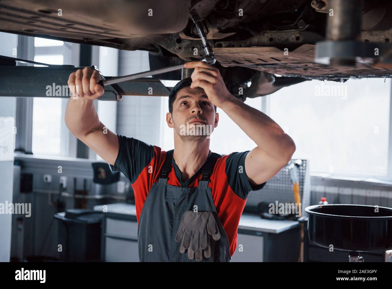 El hombre en el taller de uniforme, corrige las piezas rotas de los  automóviles modernos Fotografía de stock - Alamy