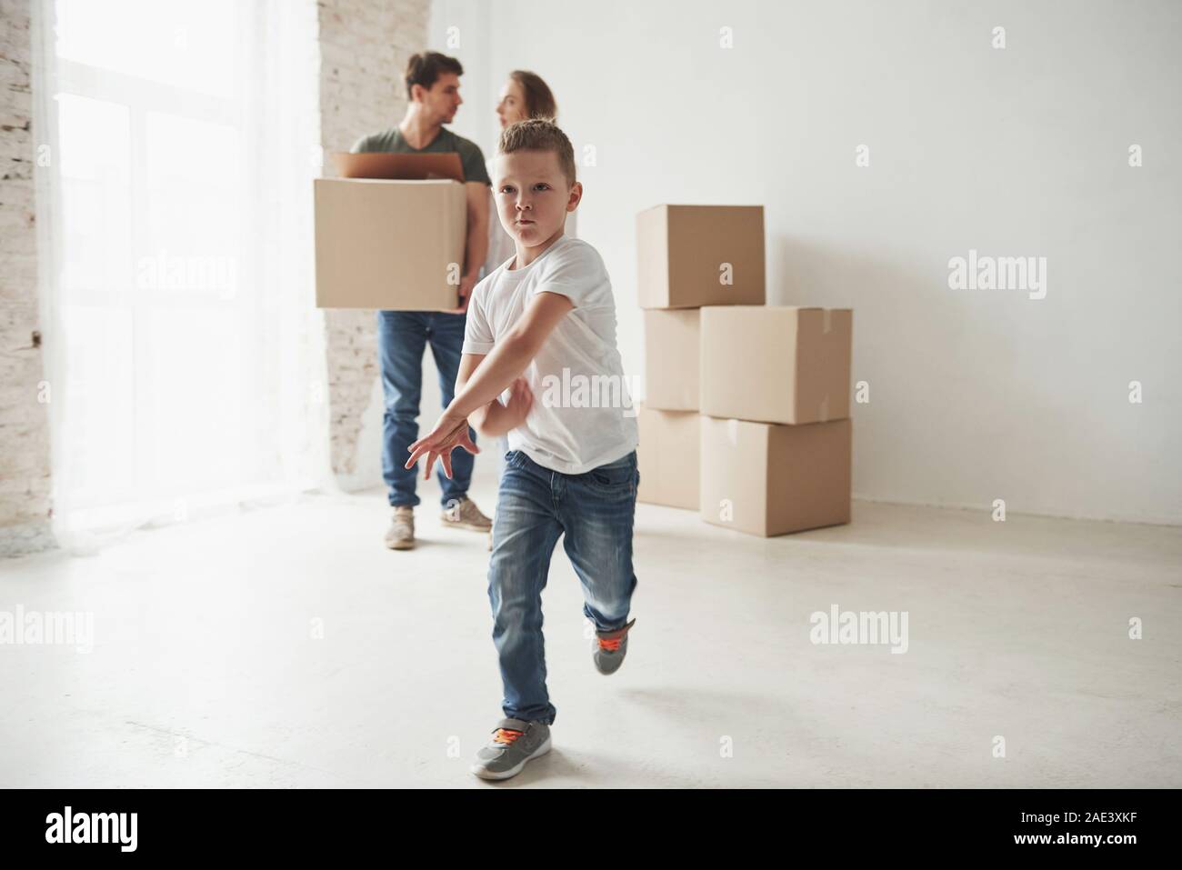 Delante de los padres. Buen humor del cabrito. Extracción tienen familia en la nueva casa. Desembalaje de cajas de mudanza Foto de stock