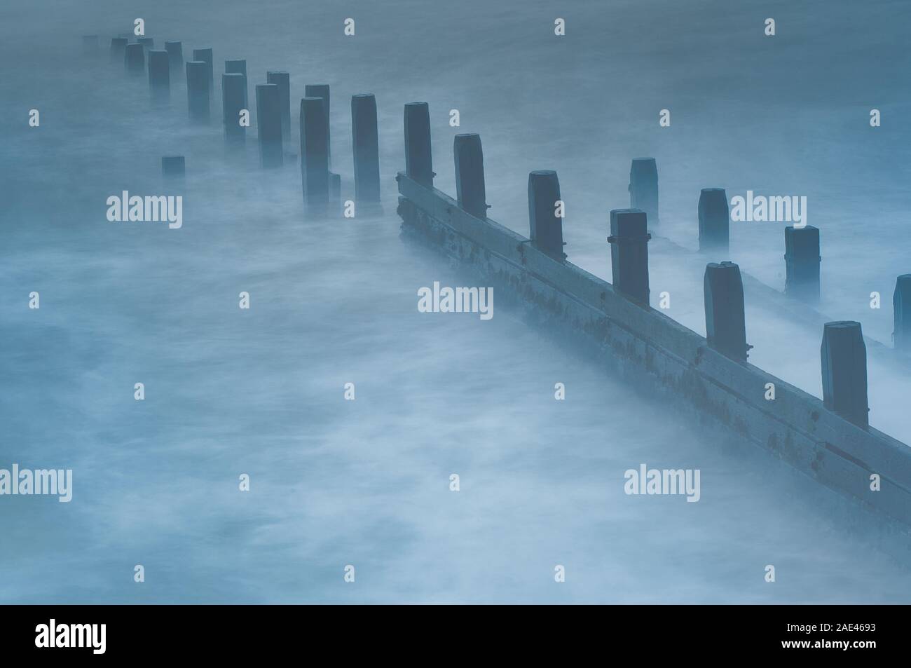 La larga exposición de las olas rompiendo sobre una ola de madera romper capeado puestos ofreciendo una línea líder en el mar del Norte. Concepto costera pacífica Foto de stock