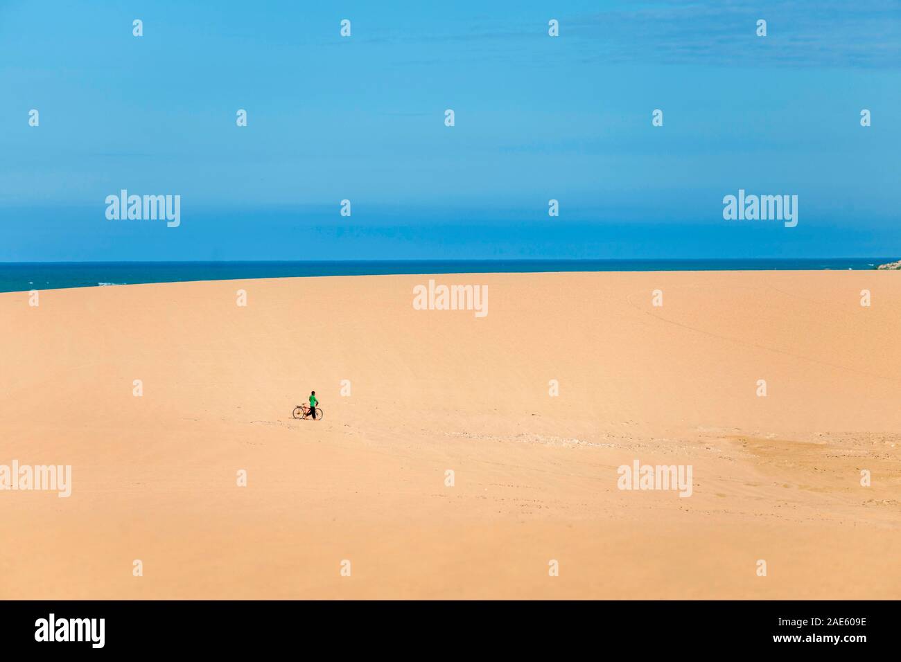 El hombre con su bicicleta en las dunas costeras de Taroa, la península de La Guajira, norte de Colombia. Foto de stock