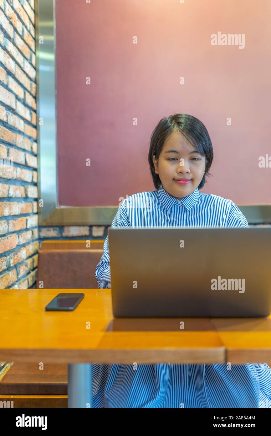 Retrato de mujer joven feliz con un portátil en lugar de trabajo bien decorada Foto de stock