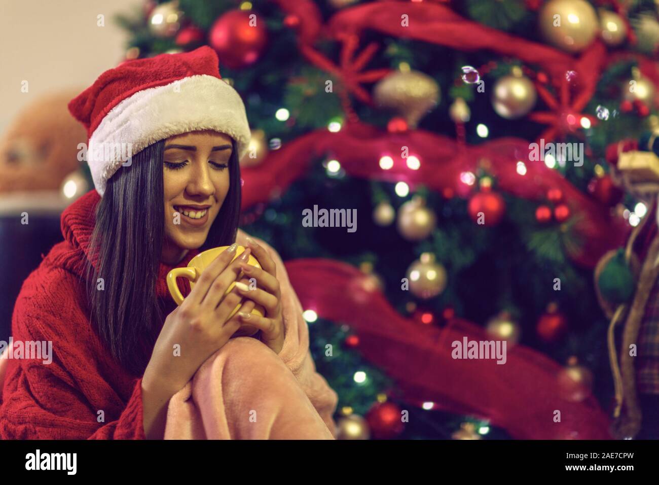 Mujer sonriente bebiendo té taza en la víspera de Navidad Foto de stock