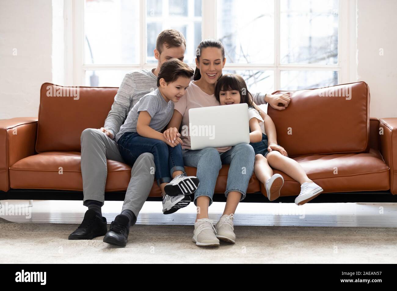 Familia Feliz con dos hijos con buen tiempo utilizando el portátil. Foto de stock