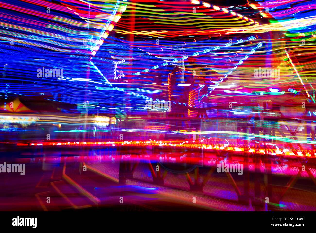 Las luces multicolores de un carnaval ride blur como el paseo de los espines en la noche. Foto de stock