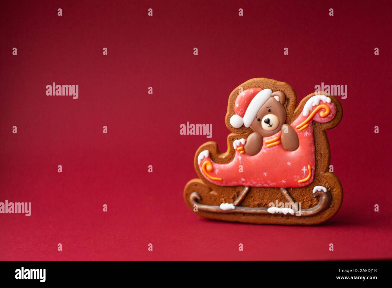 Gingerbread cookie de oso de peluche en trineo sobre fondo rojo. Los alimentos tradicionales de Navidad. Vacaciones de Navidad y Año Nuevo concepto. Copyspace. Foto de stock