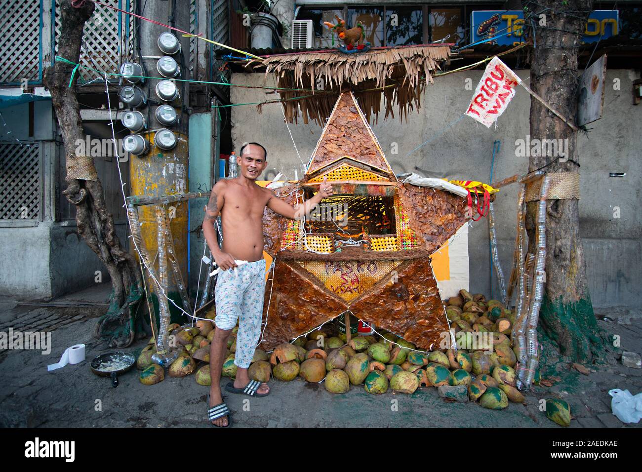 Un Filipino residente en una zona pobre de la ciudad de Cebu, posa junto a su creación artística conocida como Parol que él construyó para el período de Navidad Foto de stock