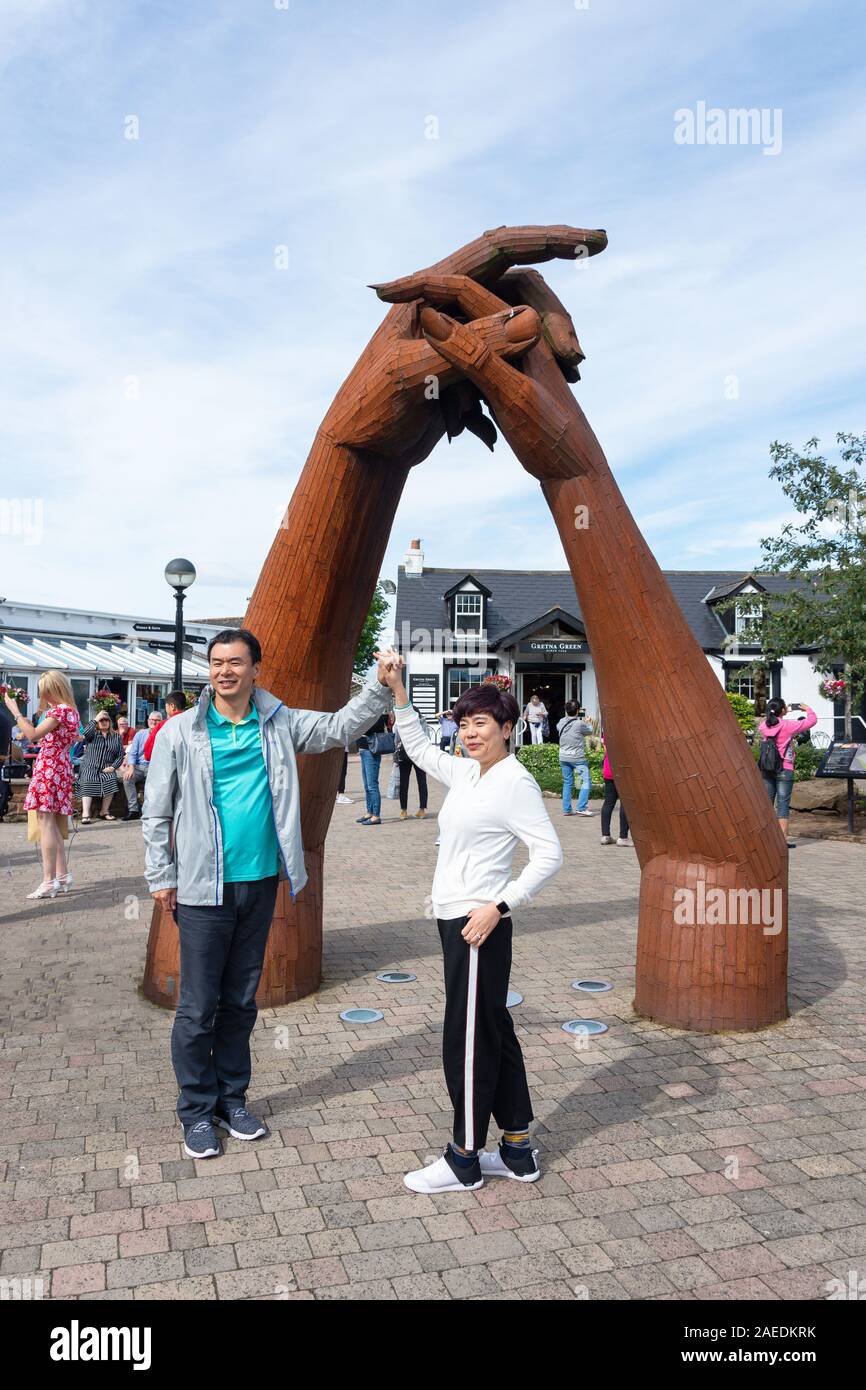 Pareja con la mano sosteniendo la escultura de Gretna Green, famoso Herreros Shop, Gretna Green, Gretna, Dumfries y Galloway, Escocia, Reino Unido Foto de stock