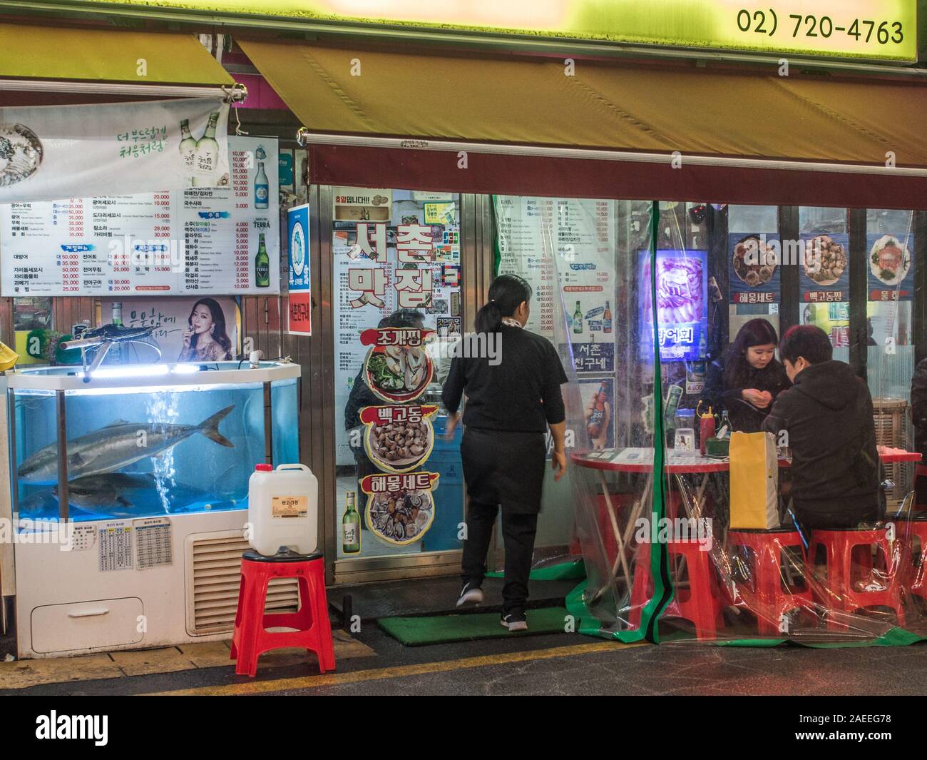 Restaurante con menú, publicidad exterior, Fish Tank, la gente en pared de plástico comedor al aire libre, noche street, Gyeongbokgung, Seúl, Corea del Sur Foto de stock