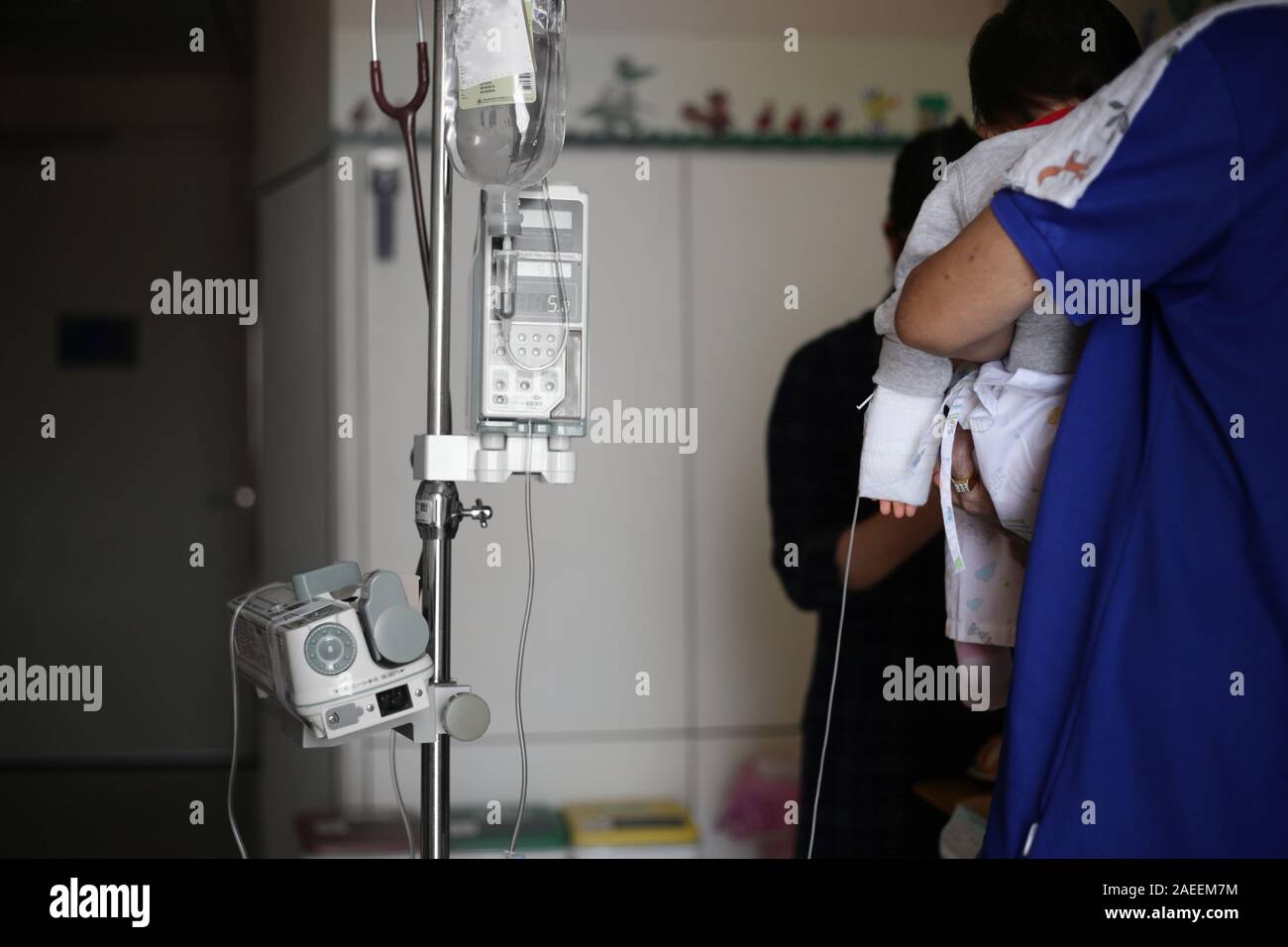 Infusión salina. enfermedad del bebé hacia adentro paciente sentado en las piernas de padres. El bebé en el hospital alimentándose. enfermos cabrito en proceso de tratamiento, en el hospital y el cuidado por Foto de stock