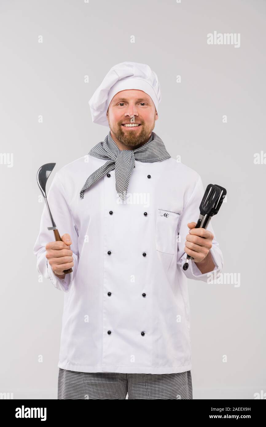 Exitoso chef joven barbudo de uniforme la celebración de menaje y mira  Fotografía de stock - Alamy