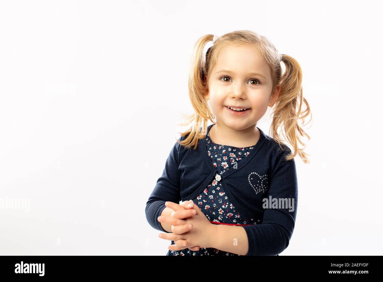 Retrato de estudio de una chica rubia de 3 años de edad y con una feliz expresión positiva. Foto de stock
