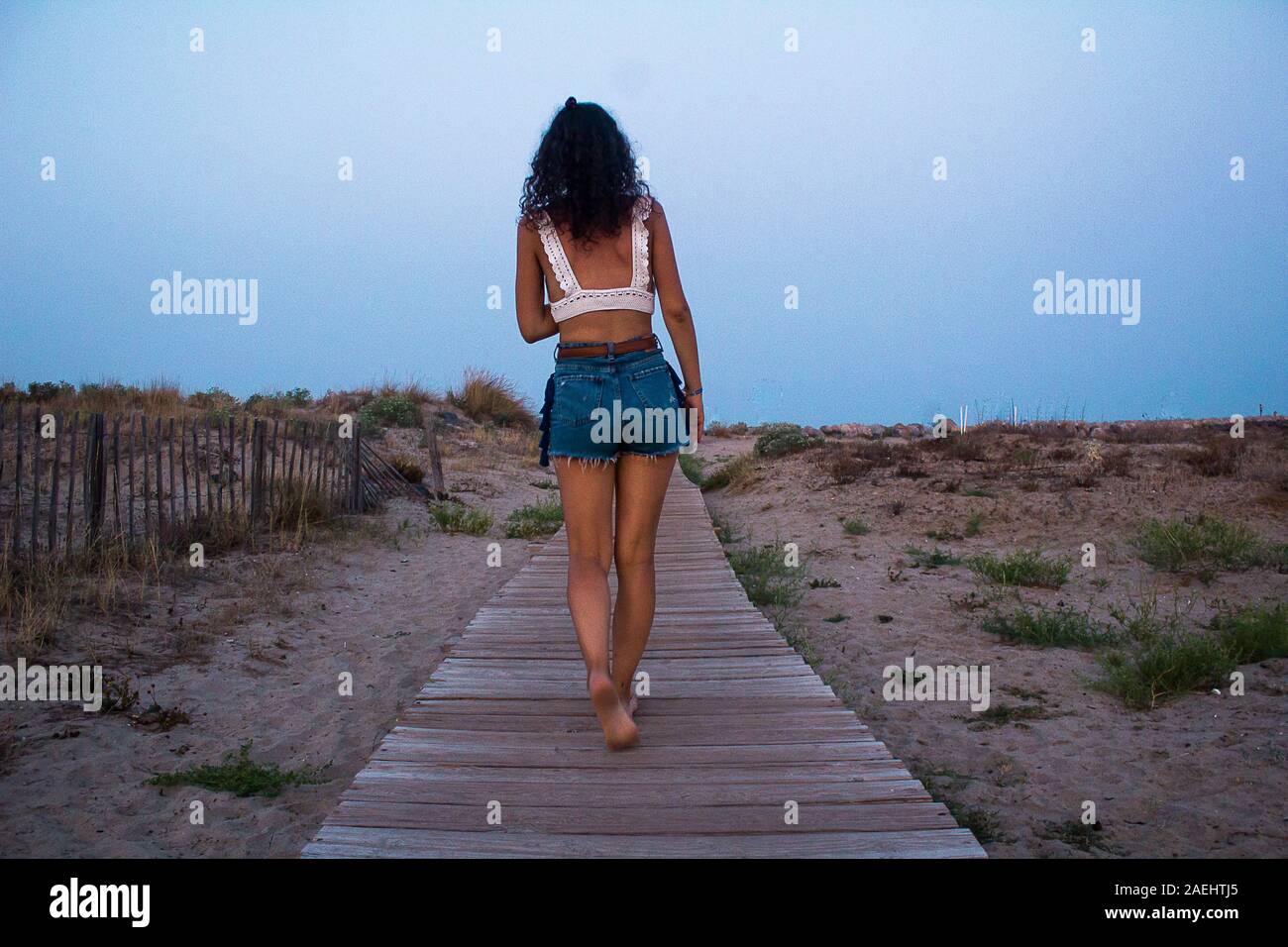 Mujer caminar sobre la pasarela de madera en la playa. Foto de stock