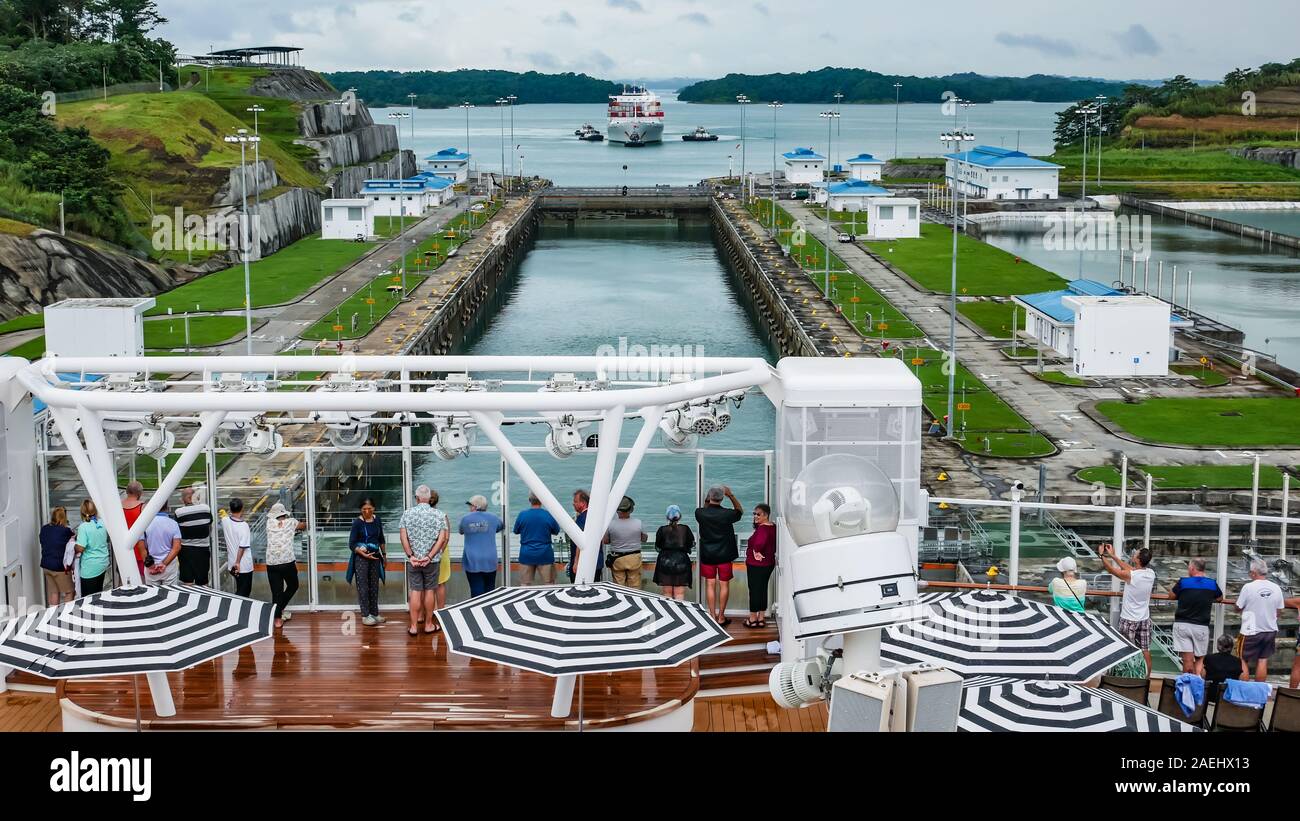 La vista de los pasajeros en la parte trasera de un crucero de lujo cruzar Agua Clara se bloquea con un barco de contenedores a la espera de entrar en los bloqueos como fondo Foto de stock