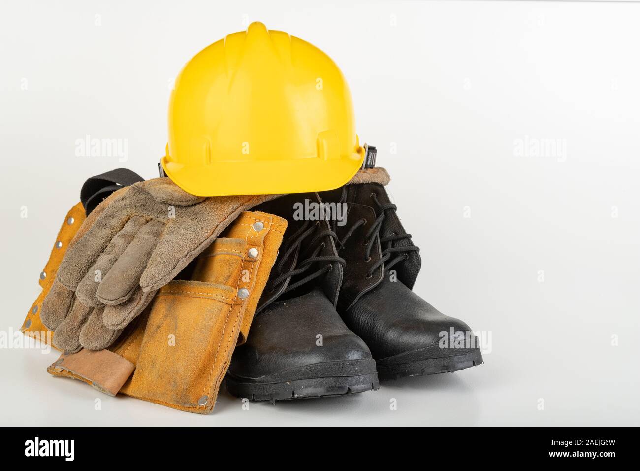 Casco, guantes y botas de trabajo sobre una tabla en blanco. Ropa de  trabajo para el trabajador de producción. Luz de fondo Fotografía de stock  - Alamy
