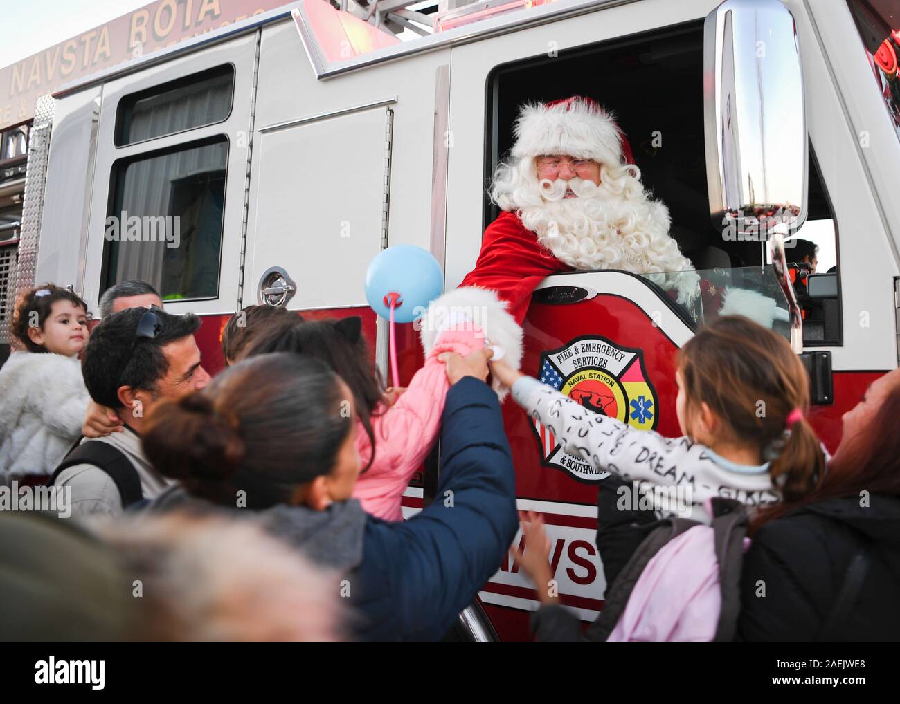 Santa Claus saluda a los niños como él llega por camión de bomberos durante la reunión anual de la iluminación del árbol de Navidad Winter Wonderland evento en la Estación Naval estadounidense de Rota, el 7 de diciembre de 2019 en Rota, España. Foto de stock