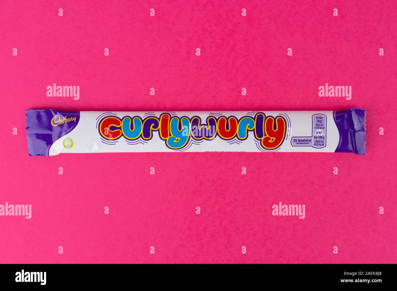 Una barra de chocolate Cadbury's Curly Wurly disparó sobre un fondo de color rosa. Foto de stock