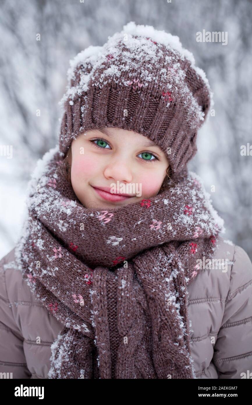 Chica con un tapón de lana cubierto de nieve en invierno Foto de stock