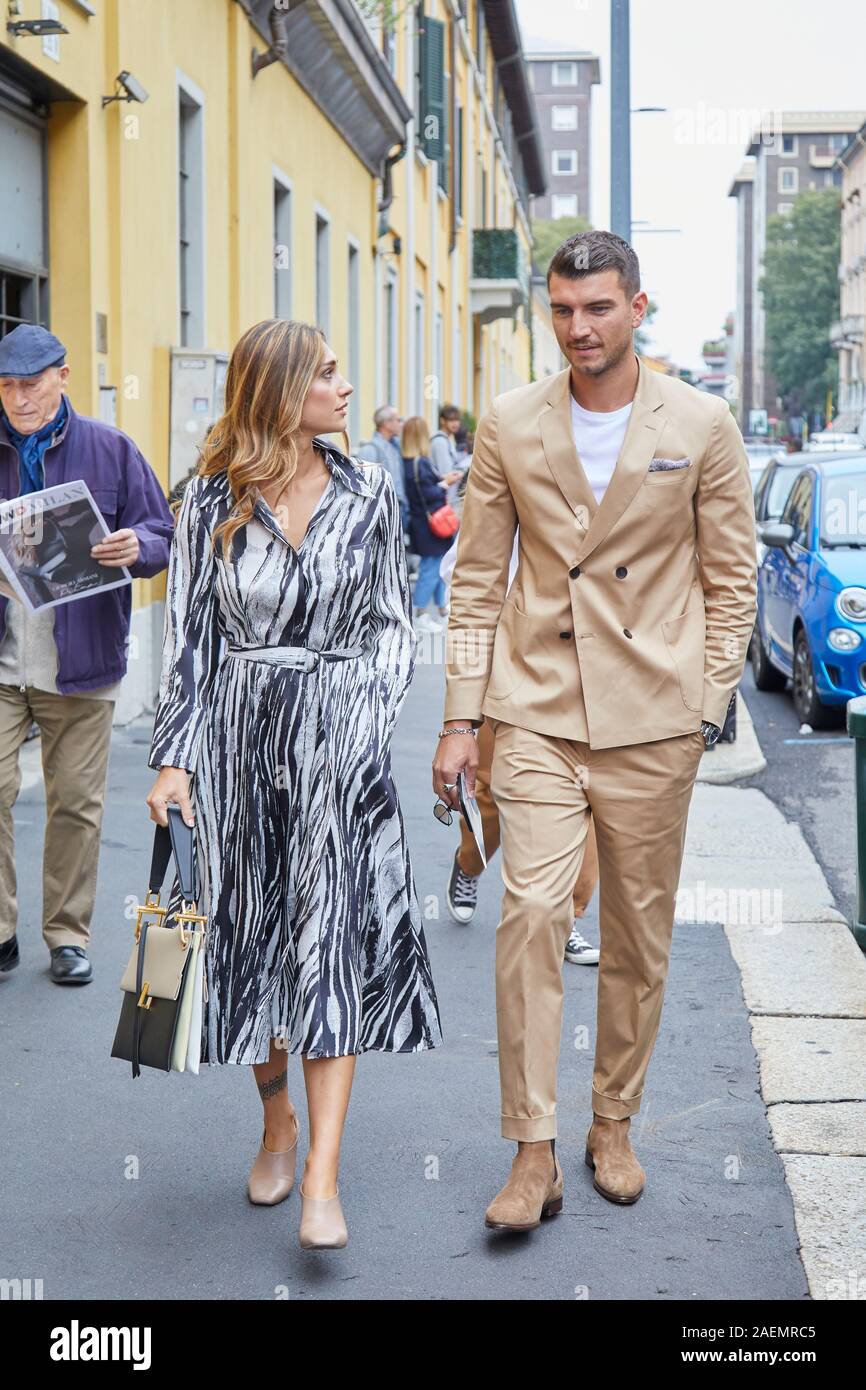 Milán, Italia - 22 de septiembre de 2019: el hombre con traje de color  beige y la mujer con el vestido blanco y negro antes de Boss Fashion Show,  la Semana de