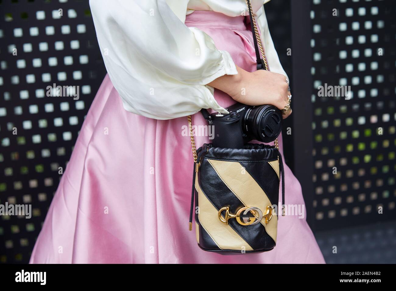 Milán, Italia - 22 de septiembre de 2019: Una mujer con tonos beige y negro bolso  Gucci , falda de satén rosado y cámara de Sony antes de Gucci Fashion Show,  la