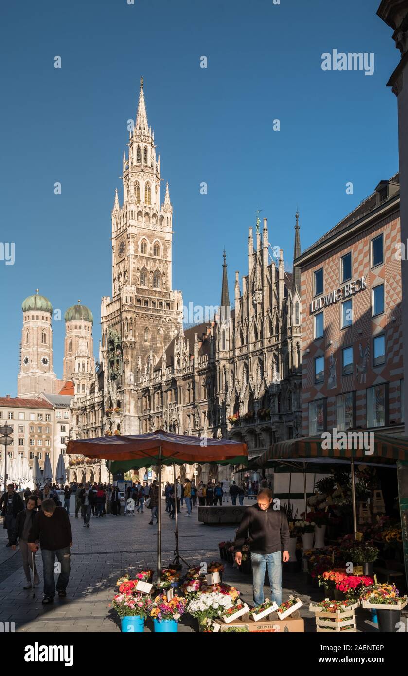 Un comerciante de mercado expone sus productos en Marienplatz, con arquitectura neogótica del nuevo edificio del Ayuntamiento, en el fondo, el casco antiguo de Munich. Foto de stock