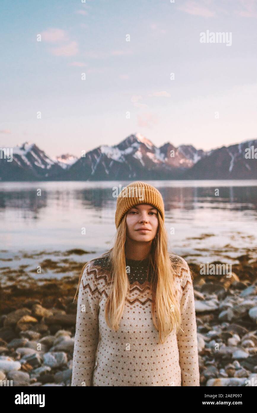 Mujer escandinava viajes vacaciones de aventura al aire libre en Noruega atardecer montañas y fiordo paisaje cabello rubio chica suéter ropa y sombrero de otoño Foto de stock