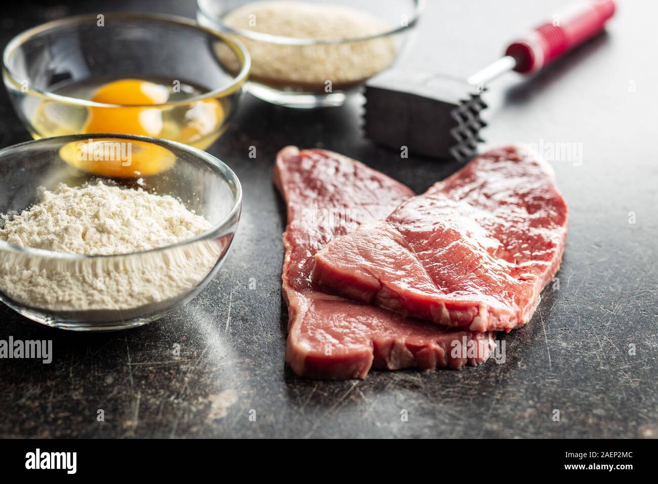 Materias Milanesa de ternera. Carne cruda en la mesa de la cocina antigua. Foto de stock