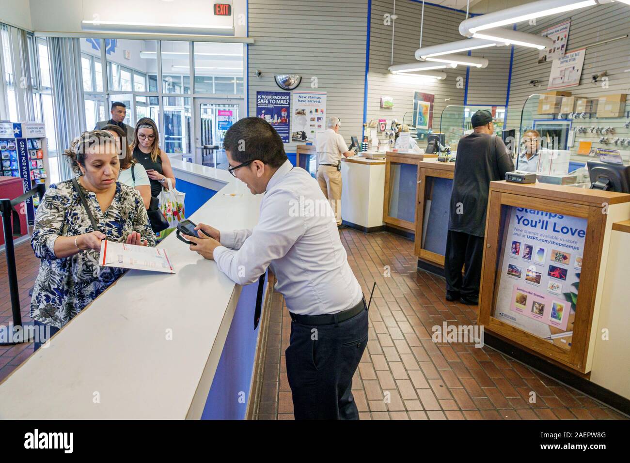 Orlando Florida, Lake Buena Vista USPS, correo de la oficina de correos dentro del mostrador de trabajador postal, empleado cliente hispano hombre línea mujer cola escáner de mano Foto de stock