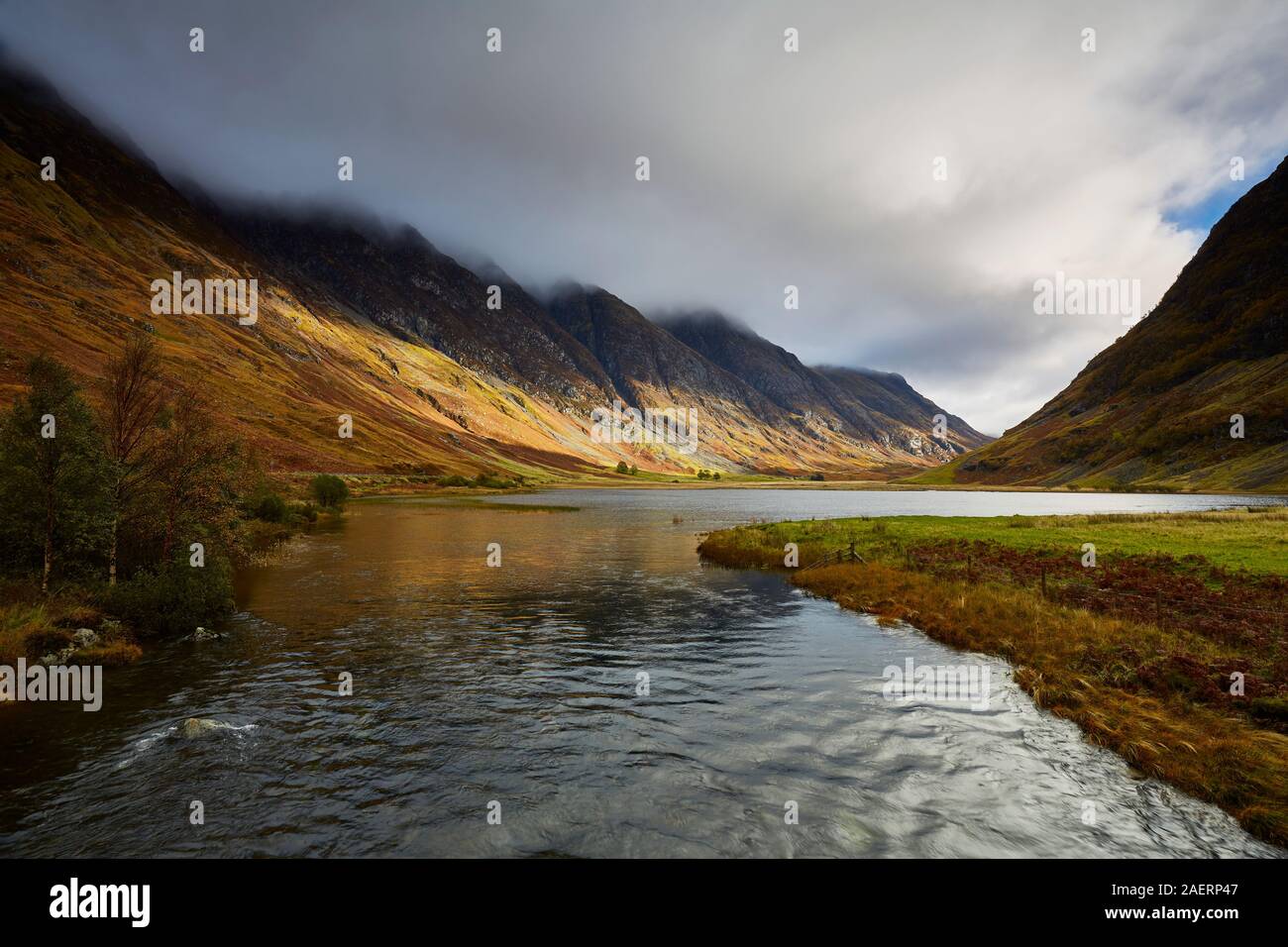 Una vista del río Coe ejecutando junto con el pase de Glen Coe en otoño con las nubes bajas que cubren las cimas de las montañas, Scotland, Reino Unido Foto de stock