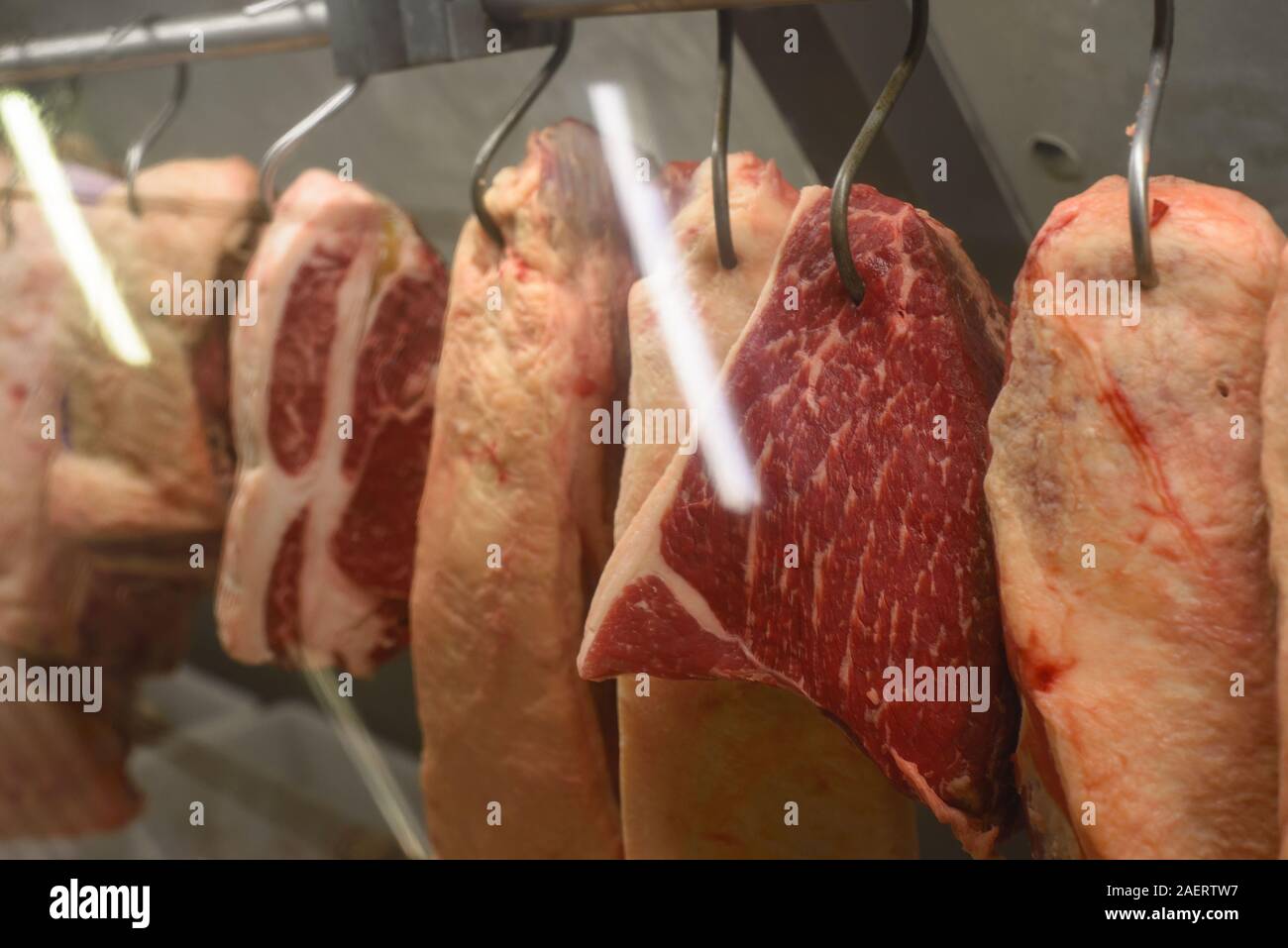 La carne colgando de los ganchos en la carnicería Foto de stock