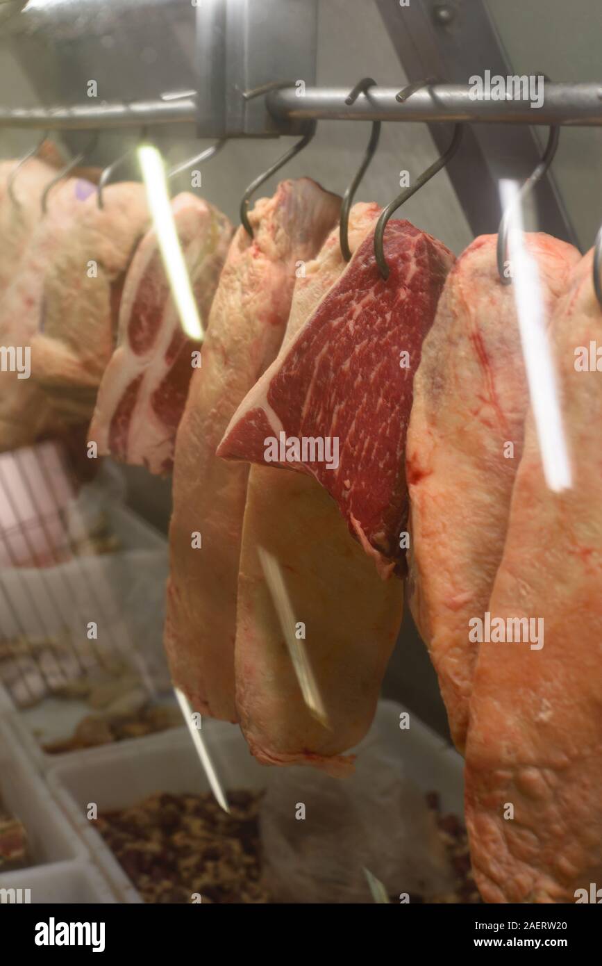 La carne colgando de los ganchos en la carnicería Foto de stock