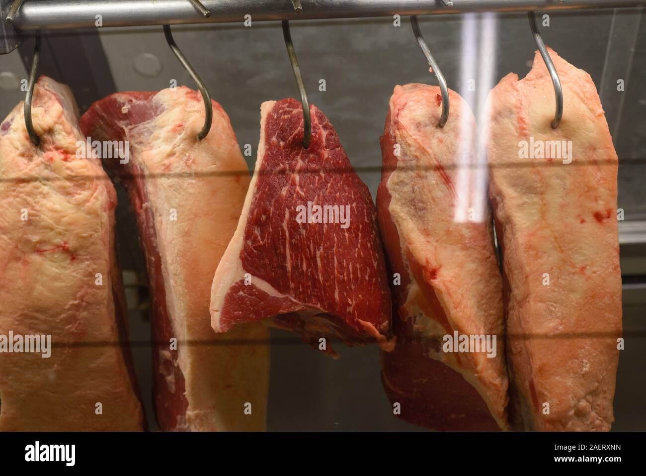 La carne colgando de los ganchos en la carnicería Foto de stock