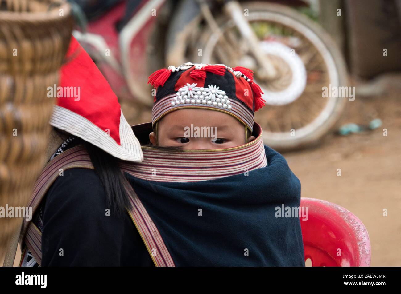 TA PHIN, LAO CAI, Vietnam - 12 de enero de 2019: un niño pequeño en una bolsa detrás de una adolescente. Los dzao rojo - una nación pequeña de Vietnam del Norte Foto de stock
