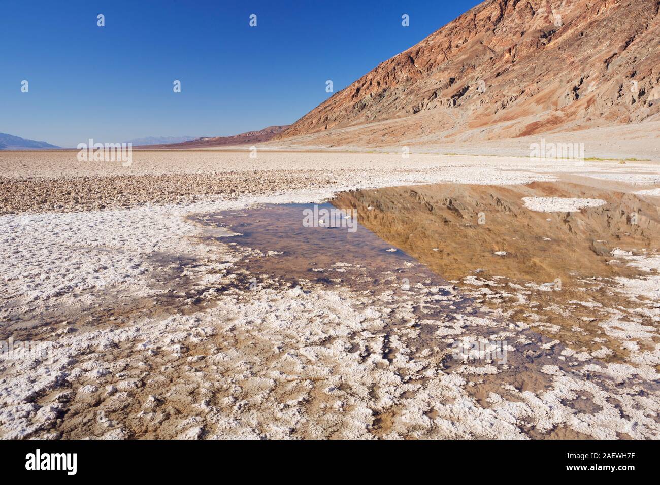 Las montañas se reflejan en el agua en la cuenca Badwater en el Parque Nacional Valle de la Muerte, California, Estados Unidos. Foto de stock