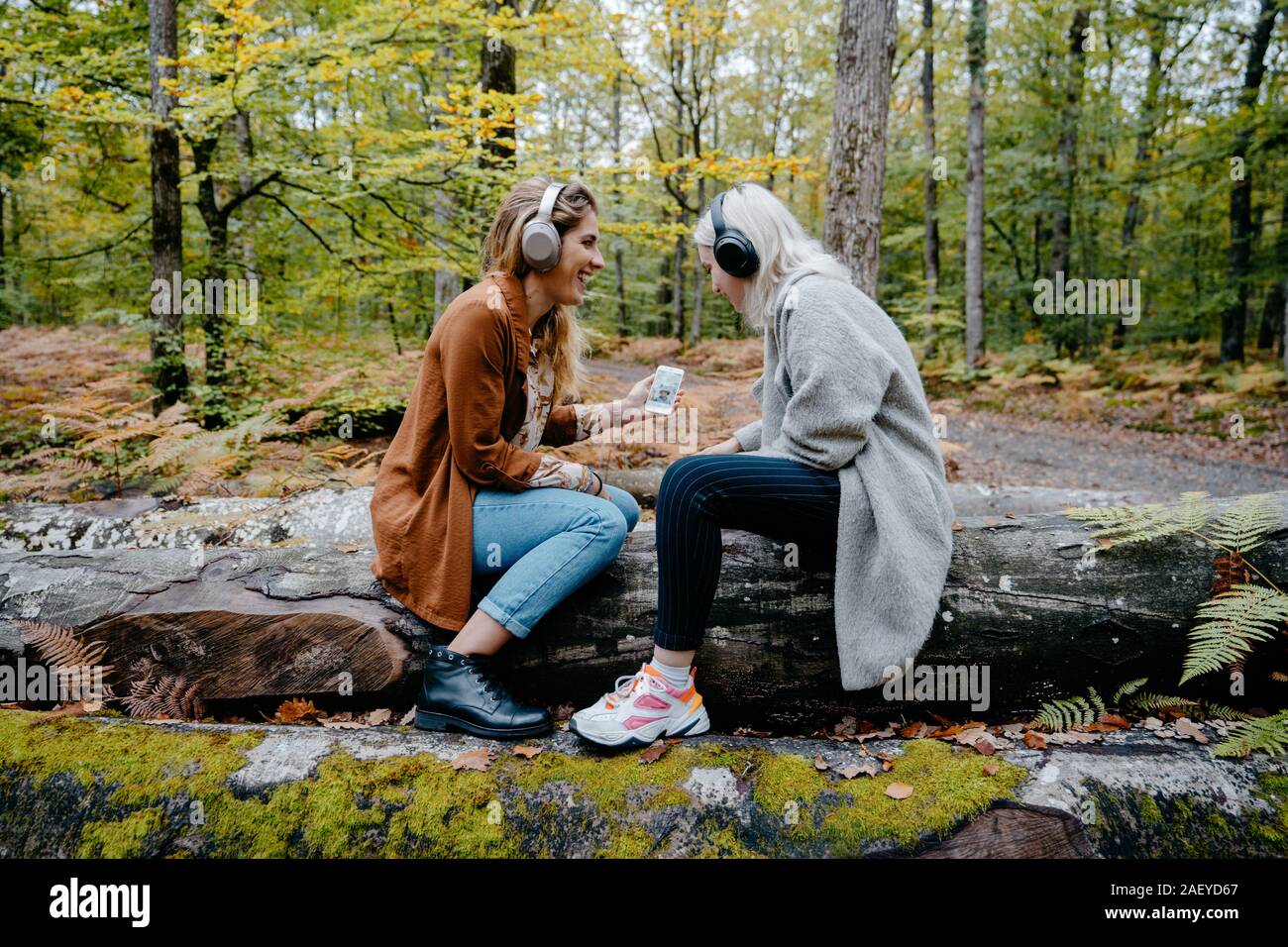 Dos mujeres streaming un vídeo sobre un smartphone en un bosque remoto Foto de stock