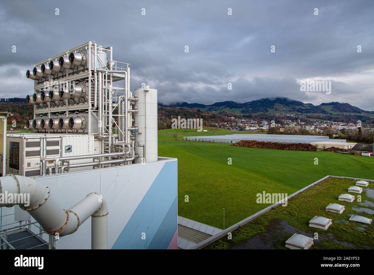 La empresa suiza Climeworks ejecutan 30 CAD - Captura de aire directo - ventiladores en el techo de esta basura incinerador en Hinwil fuera de Zurich. Fundada en 2009 por Christoph Gebald y Jan Wurzbacher, la compañía ha comercializado la unidad de captura de carbono modular, cada una de las cuales es capaz de chupar hasta 135 kg. de CO2 fuera del aire a diario. El proceso es energía exigente, y las unidades de Hilwil utilizar el exceso de energía desde el incinerador para ejecutar los coleccionistas. A su vez, el CO2 se utiliza en las cercanías de invernadero comercial (en el fondo) para aumentar el rendimiento del cultivo y también delivere Foto de stock