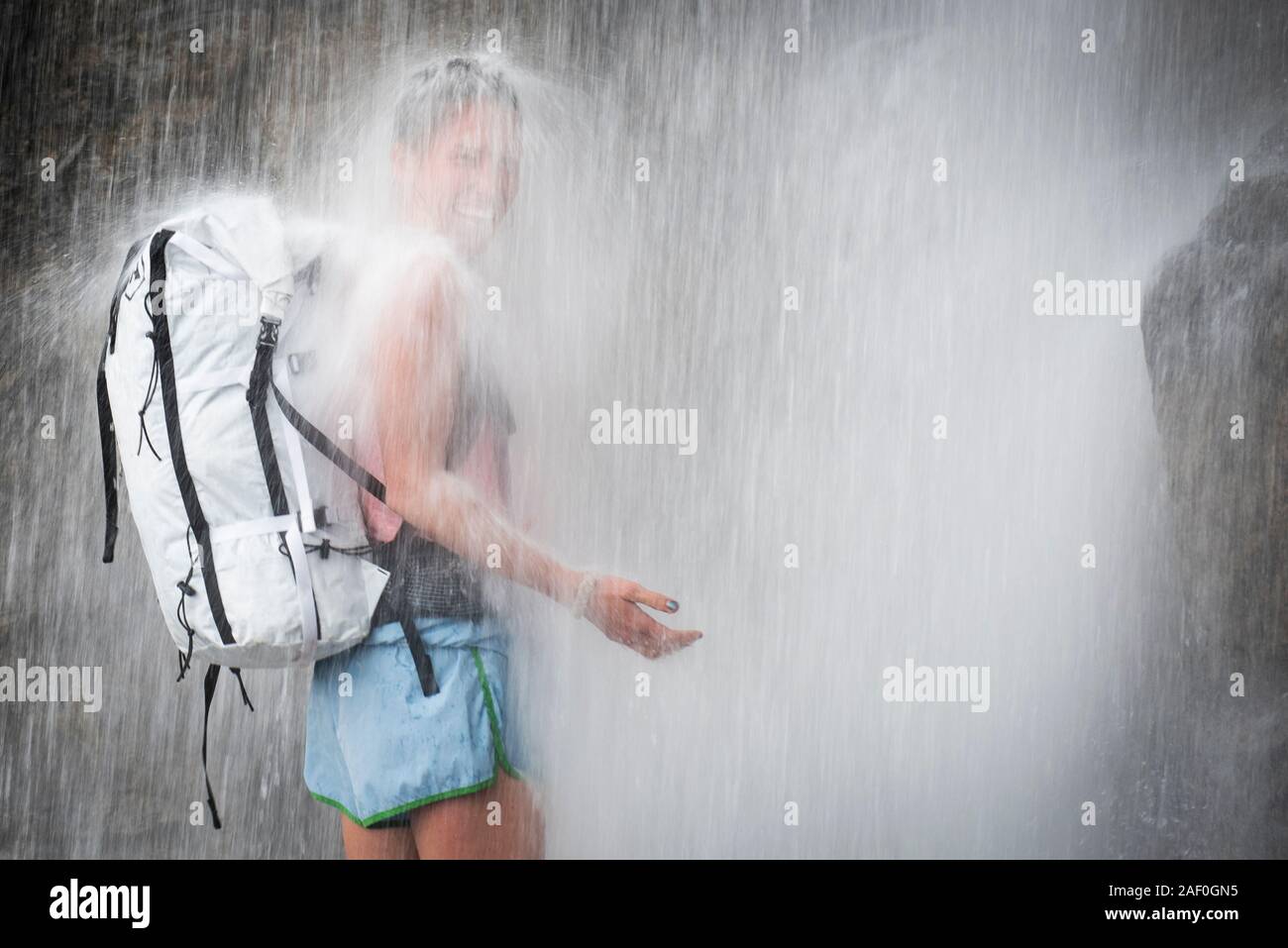 Mujer de pie riendo en cascada Foto de stock