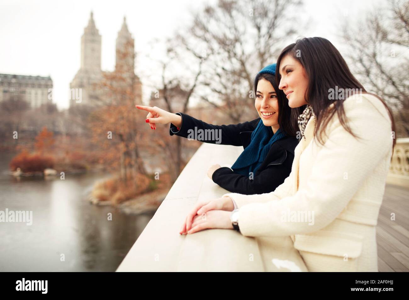 Mujer señalando a la distancia con un amigo, en las cercanías del parque de la ciudad Foto de stock