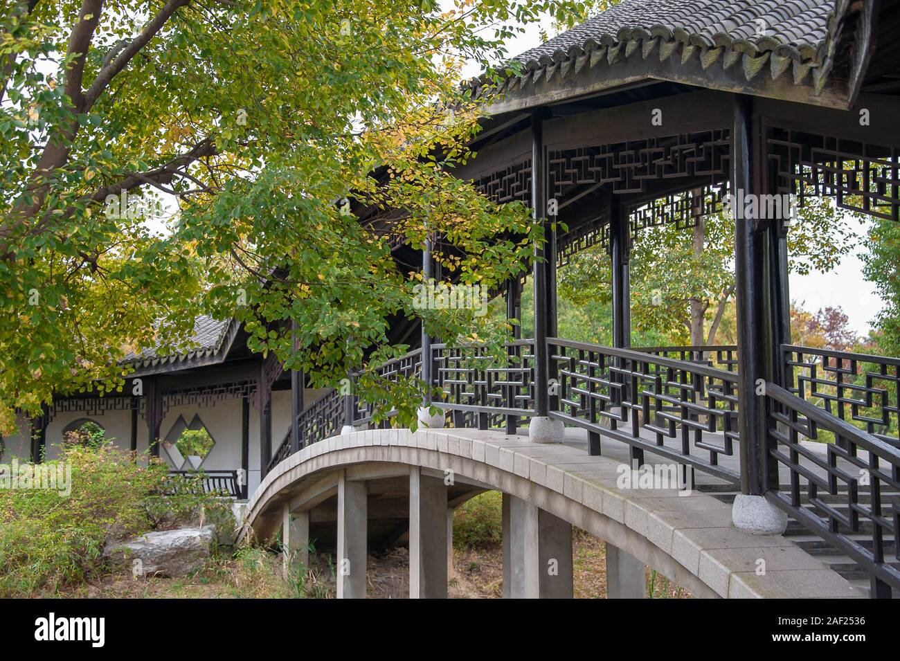 China, Wuxi, provincia de Jiangsu - puente cubierto y paseo en un tradicional jardín chino en otoño Foto de stock