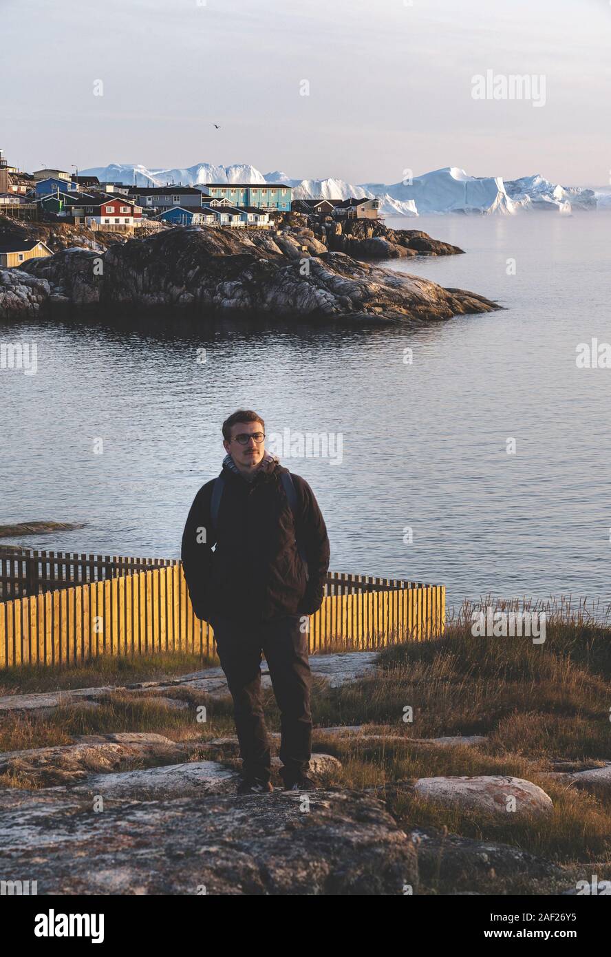 Gente sentada delante de enorme pared de hielo del glaciar. Ilulissat