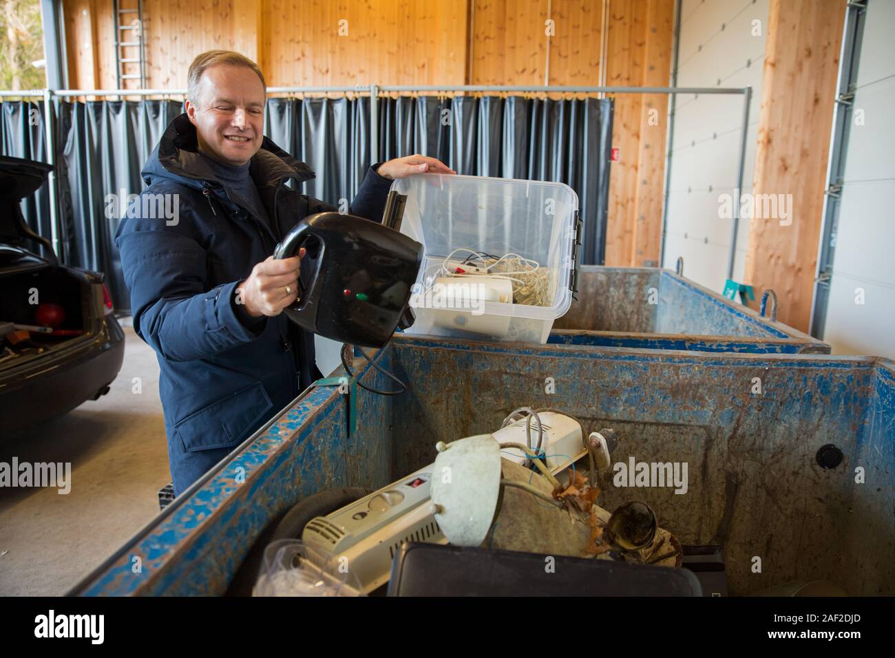 Un hombre poniendo viejos aparatos en el contenedor en el centro de clasificación para la eliminación segura y el reciclaje Foto de stock