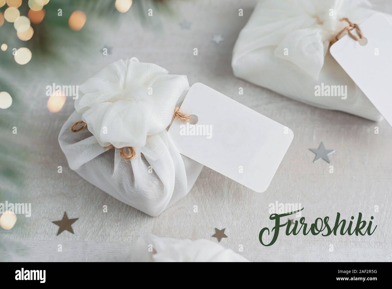 Regalo de navidad envuelto con tela furoshiki blanco con etiquetas. Eco friendly regalo. Foto de stock
