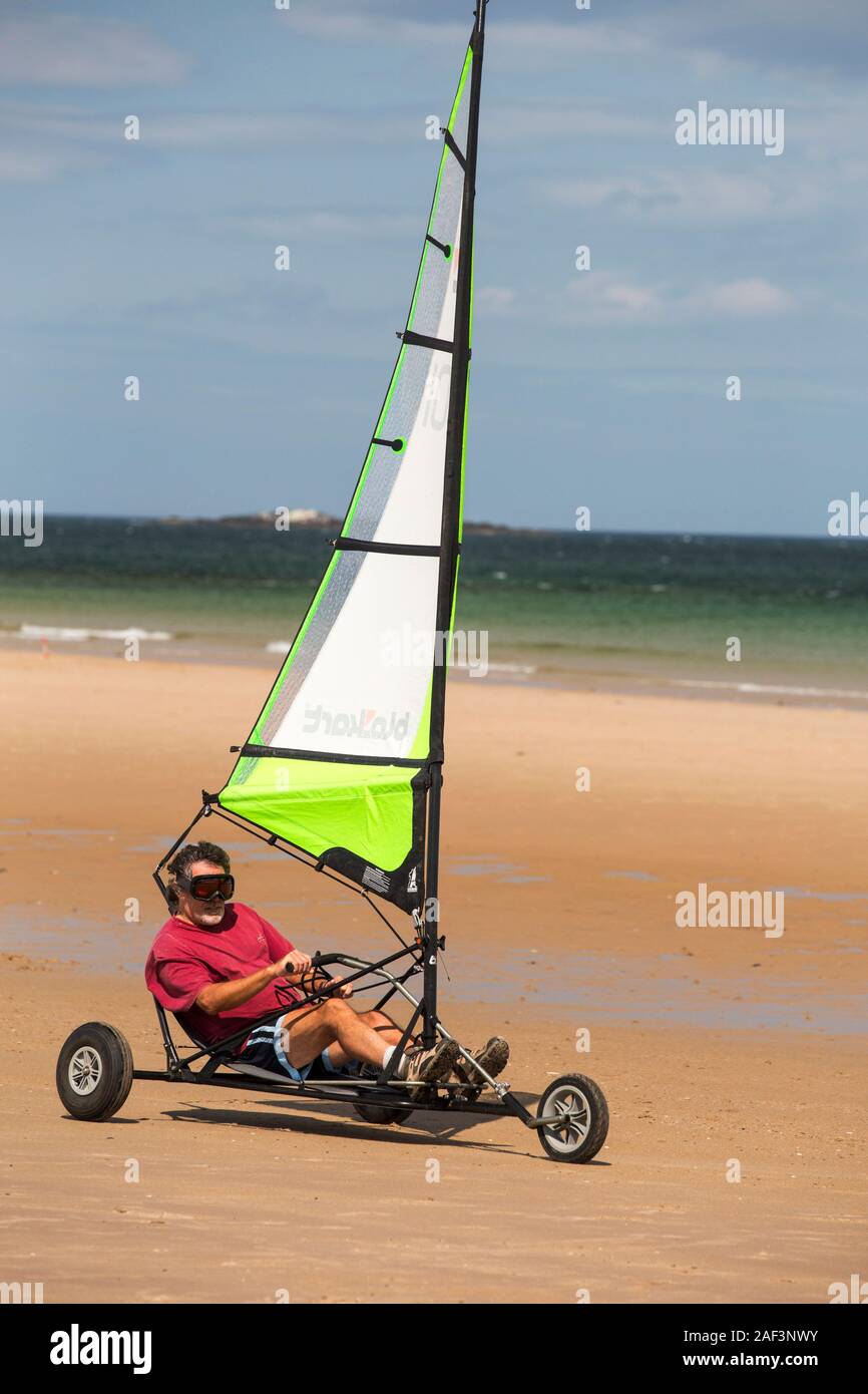 Un hombre en un yate de arena en la playa de Bamburgh en Northumberland, Reino Unido. Foto de stock