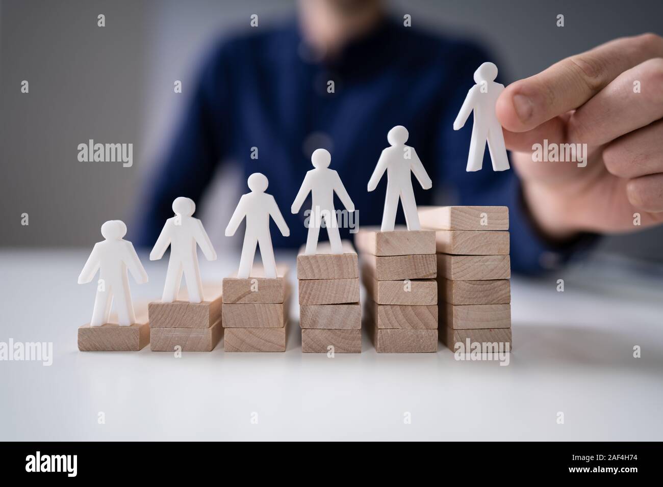 Empresario colocando la figura humana en la parte superior del bloque de madera Foto de stock