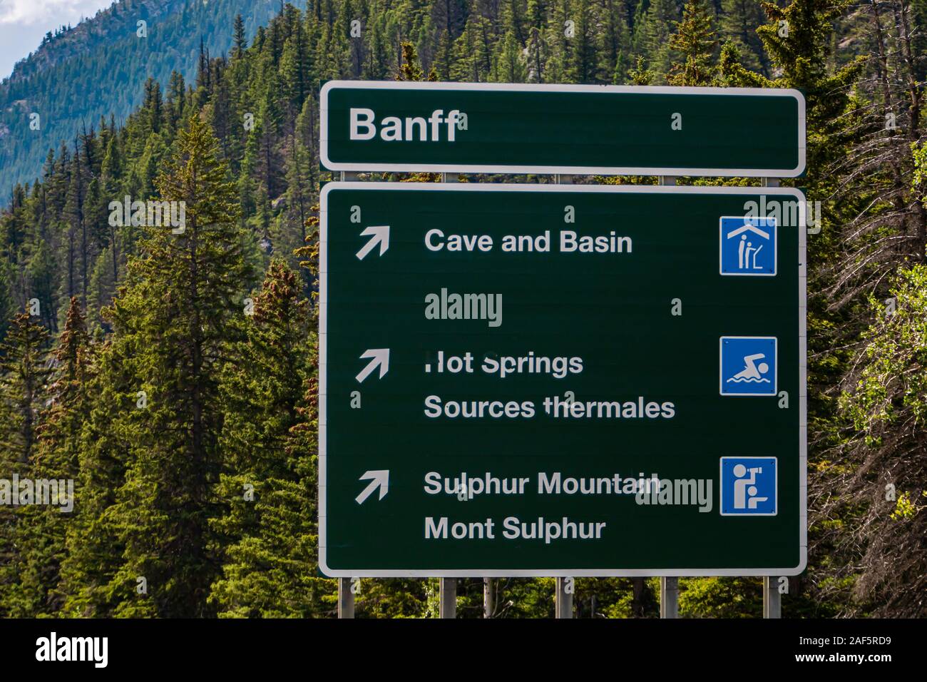Canadian dos idiomas Inglés y Francés Información road señales verdes, Banff Town, la cueva y la cuenca, aguas termales, la montaña Sulphur, Alberta, Canadá Foto de stock
