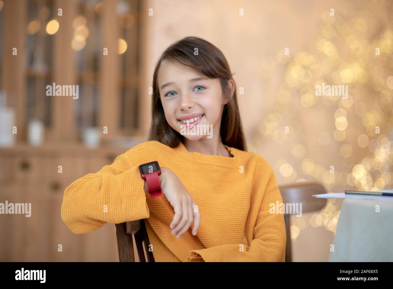 Linda chica en camiseta naranja sonriendo agradablemente Foto de stock