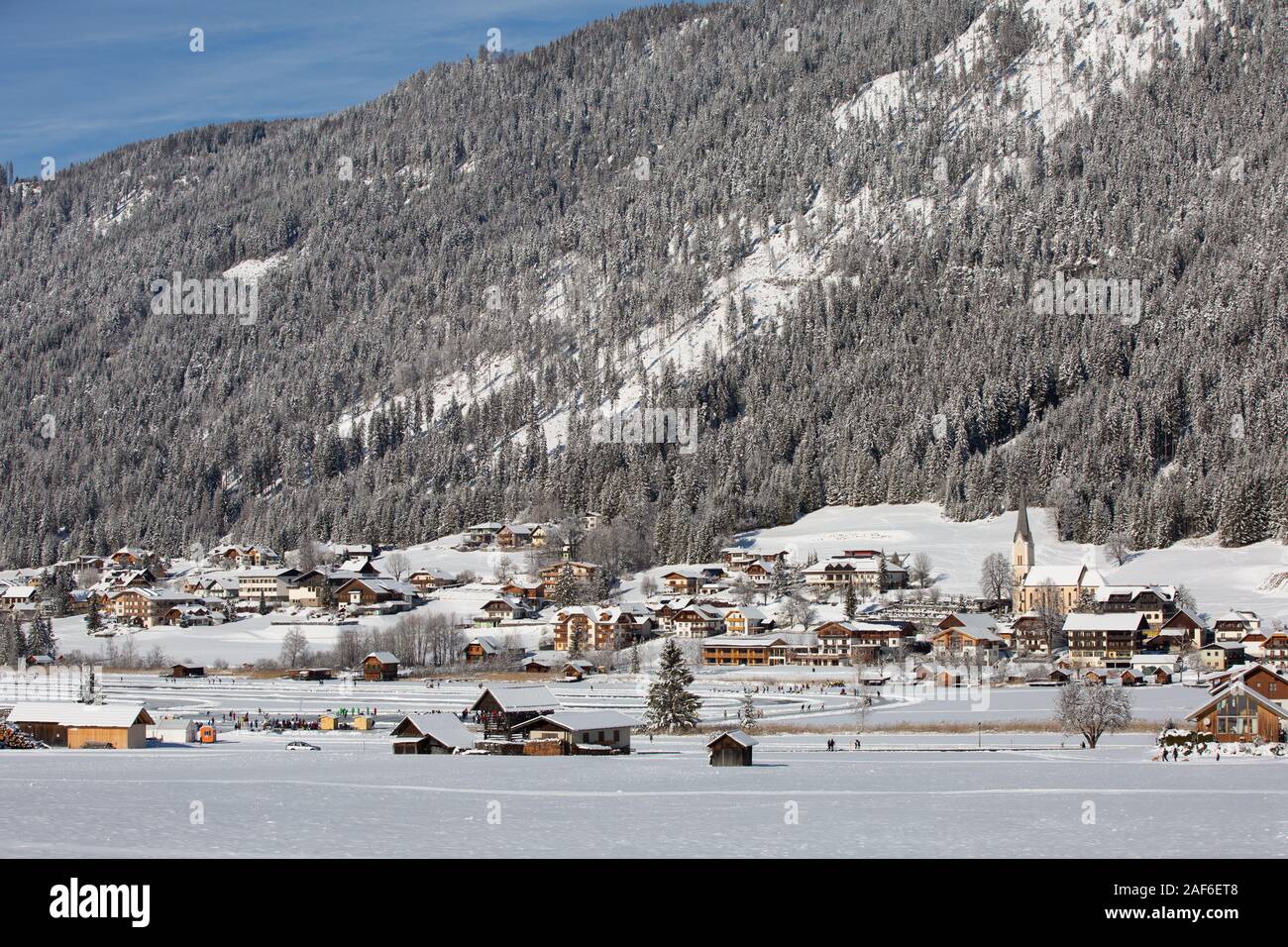 El hermoso entorno del Parque Natural de Weissensee. Turistas y habitantes de la ciudad caminando y el patinaje sobre el lago congelado Weissensee, Carintia, Alpes, Austria Foto de stock