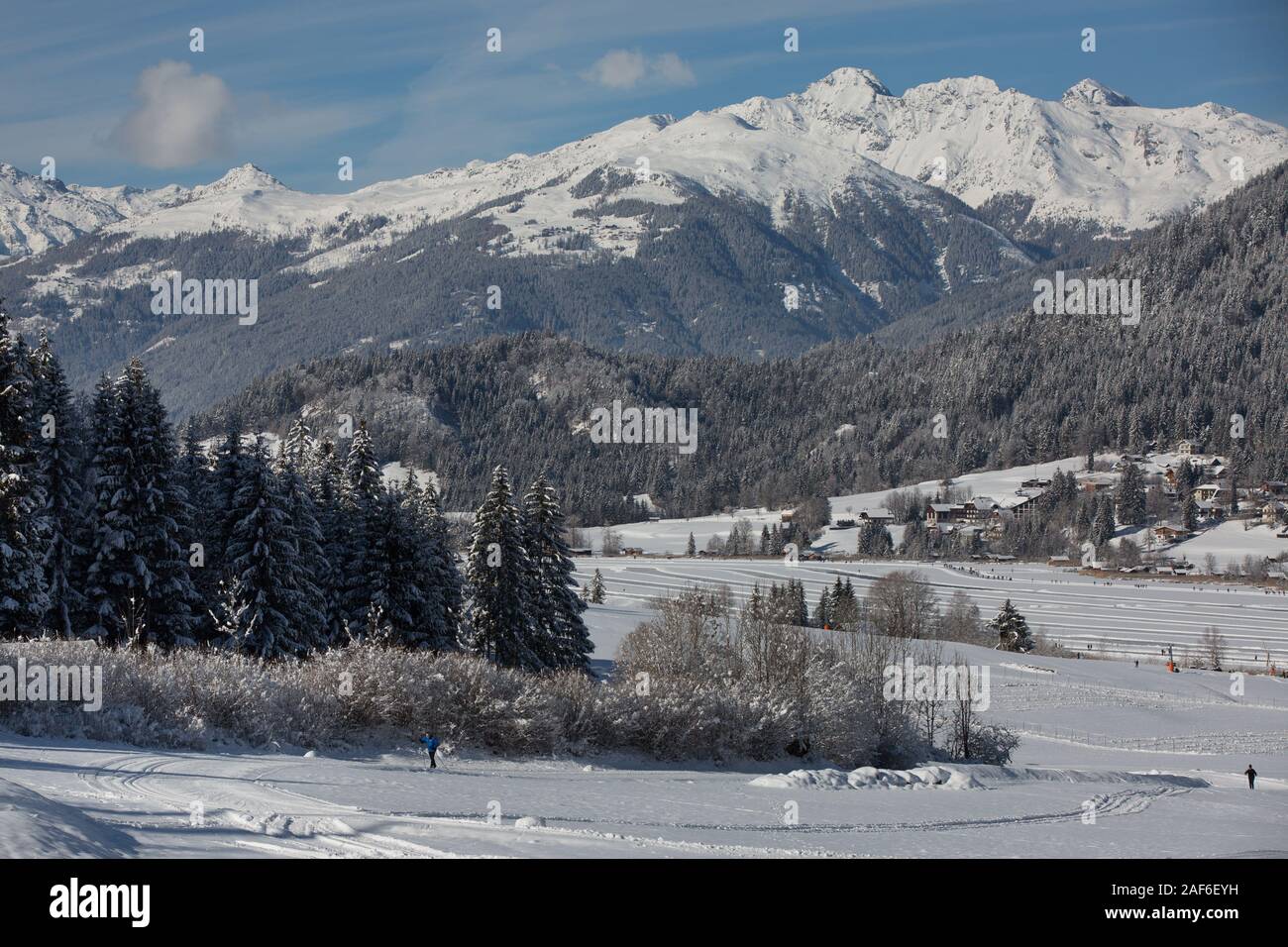 Lago congelado panorama con montañas cubiertas de nieve y bosques. La gente patinar y caminar sobre el lago congelado Weissensee, Carintia, Alpes, Austria Foto de stock